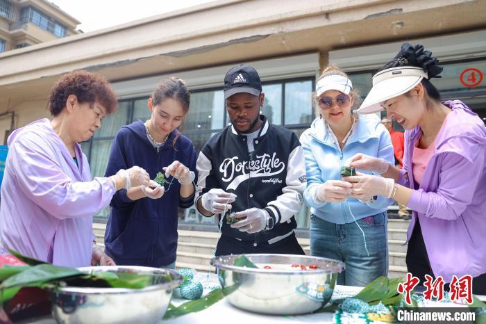 中国侨网6月5日，外籍友人学习包粽子。当日，来自俄罗斯、塔吉克斯坦、加拿大的外籍友人，在山东省青岛市沉浸式体验传统裹粽、艾草花束和艾草锤制作等端午民俗，实地感受中国传统文化的魅力和深厚的历史底蕴。　张鹰 摄