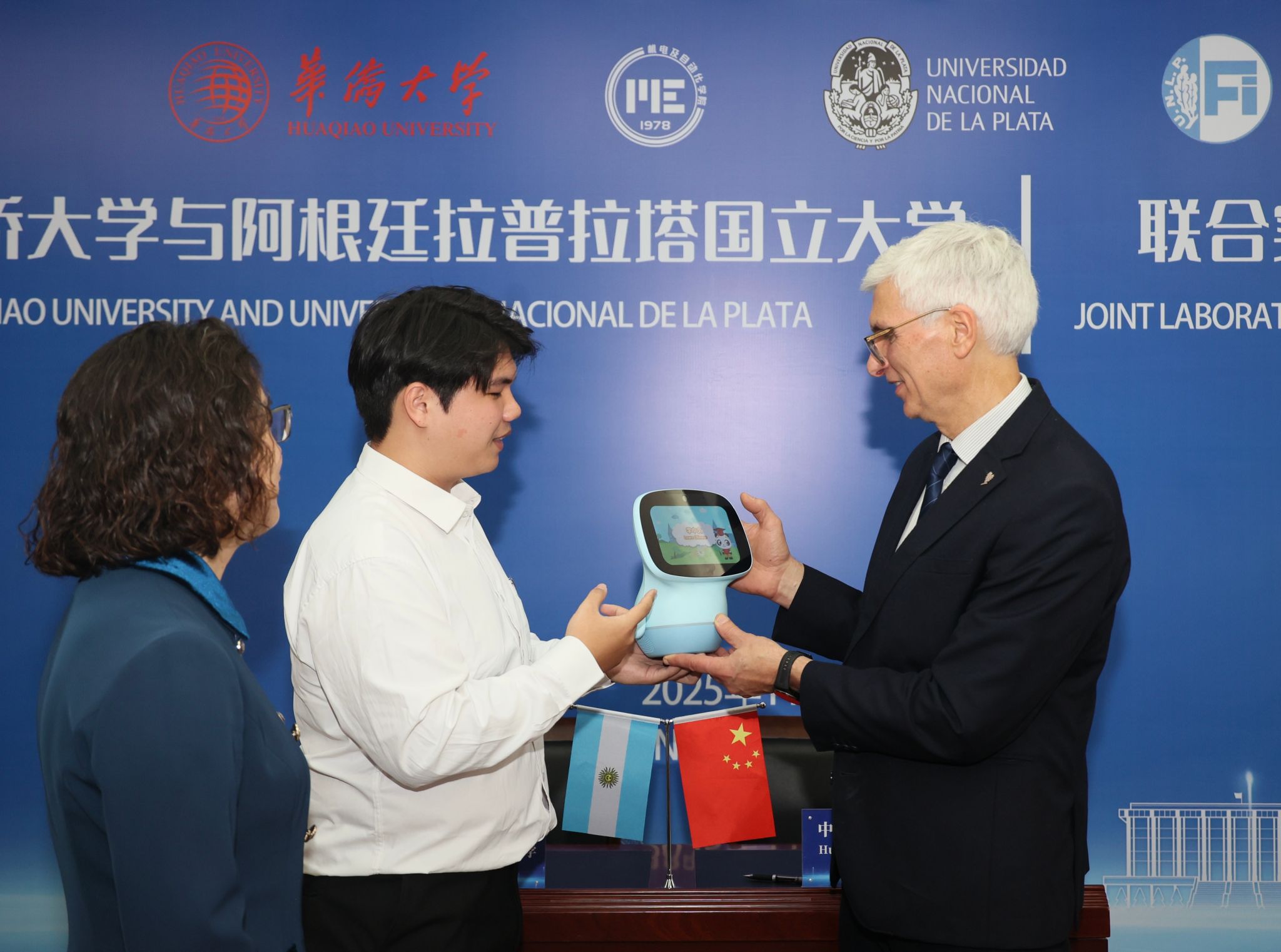 王华珍老师（左一）和杨家迅（左二）向阿根廷拉普拉塔国立大学副校长介绍华文教育机器人.jpg